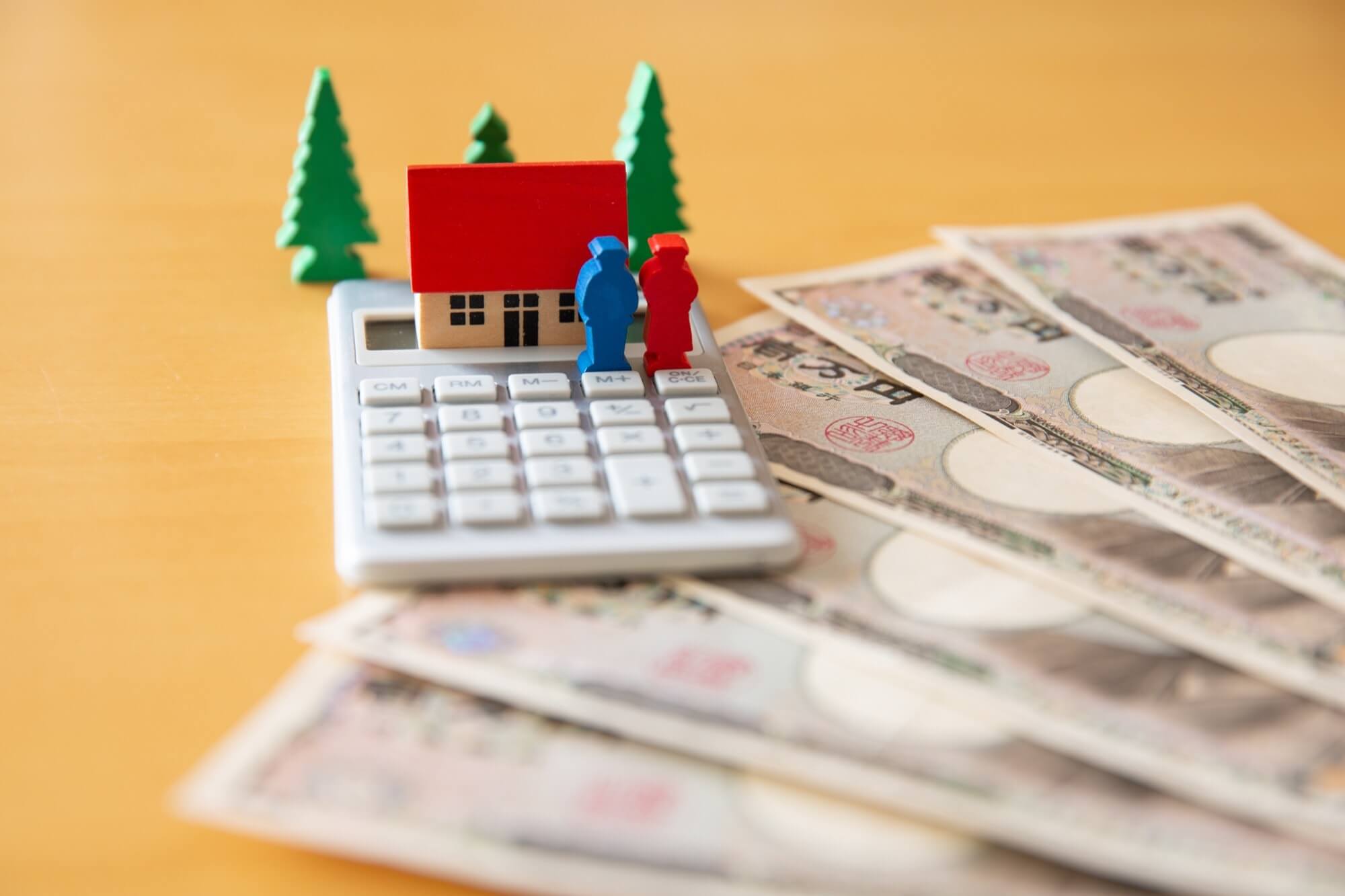 計算機の上に立つミニチュアのカップルと家