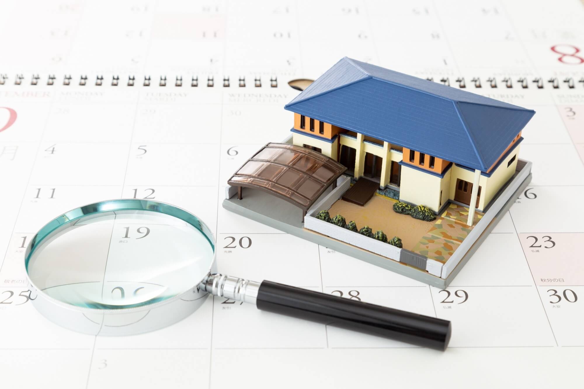 住宅模型とカレンダーと虫眼鏡