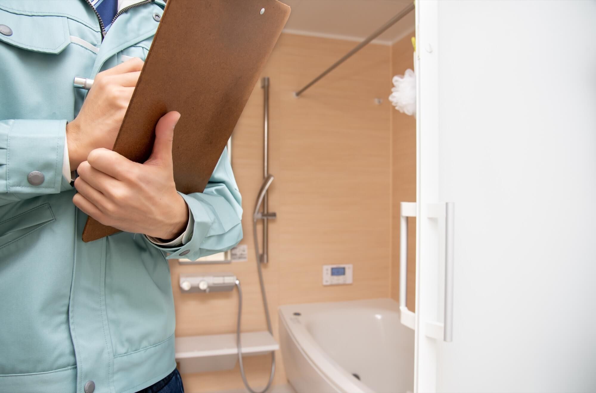 作業着を着てバスルームの点検をする男性