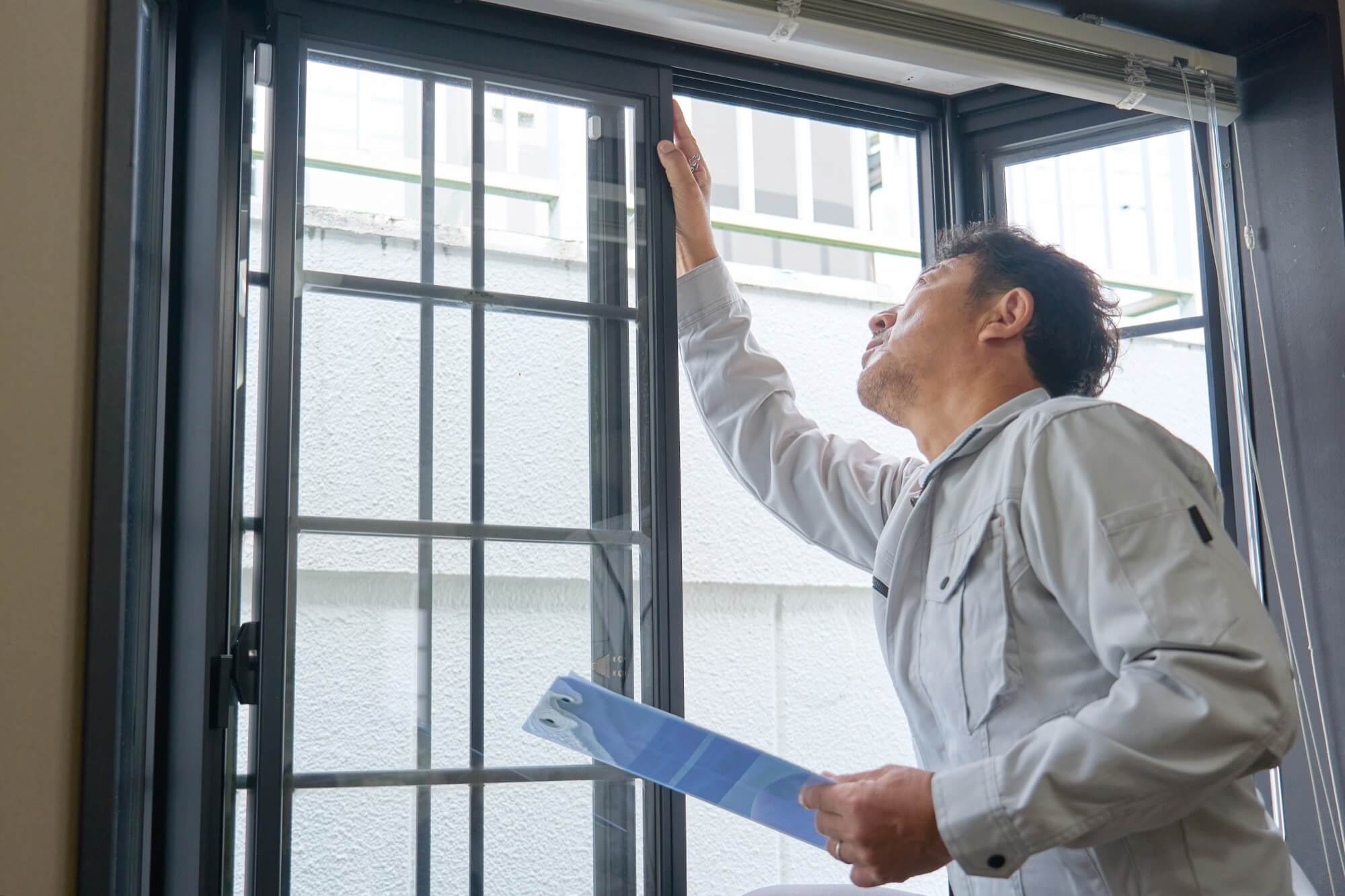 住宅の窓を点検するリフォームスタッフ