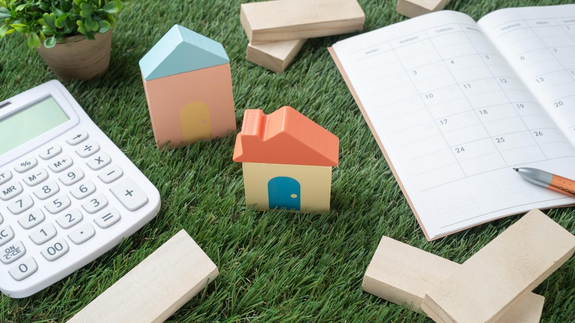 ミニチュアの家とスケジュール帳、電卓の画像