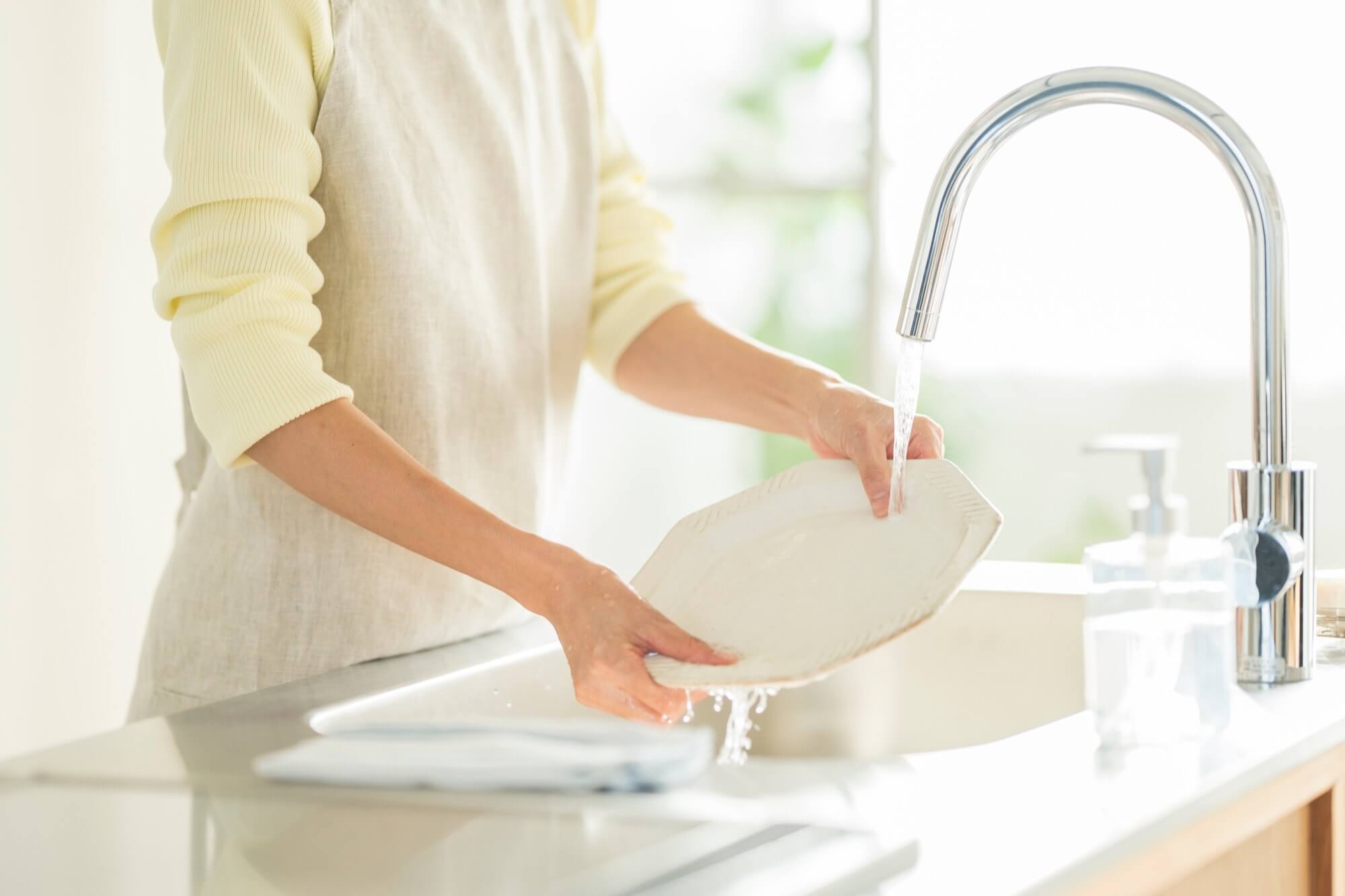 キッチンで食器を洗う女性